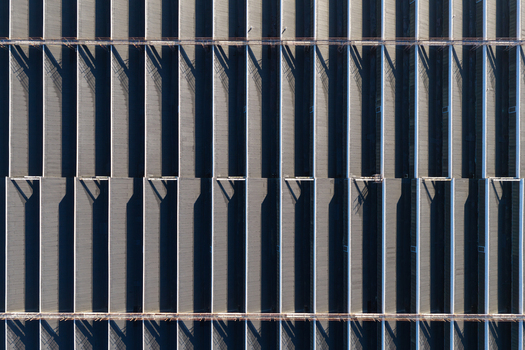 Aerial view of a warehouse roof featuring repeating structural patterns long shadows and industrial metal surfaces Warsaw Masovian Voivodeship Poland.