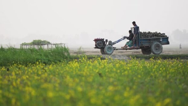 View of a power tiller driving through a rural field Bangladesh.