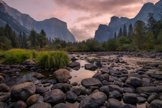 View of the Merced River flowing through Yosemite Valley with granite cliffs rocky riverbed and sunset light in Yosemite Valley California United States.