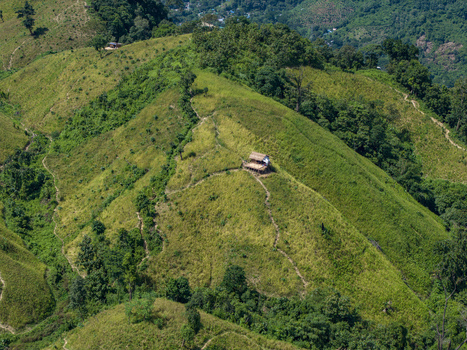 Aerial view of Shita Pahar featuring a small wooden hut perched on a grassy hillside with winding footpaths and lush vegetation in Kaptai Chittagong Division Bangladesh. Aerial view of Shita Pahar featuring a small wooden hut perched on a grassy hillside with winding footpaths and lush vegetation in Kaptai Chittagong Division Bangladesh.