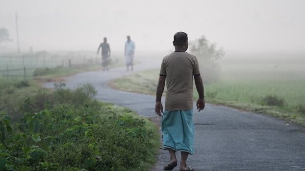 View of a man walking on a foggy rural road in Bogura Bangladesh.