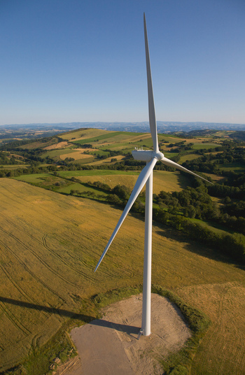 Aerial view of a solitary wind turbine standing tall amidst a patchwork of golden fields and verdant hills under a clear sky Salles Curan Occitanie France. Aerial view of a solitary wind turbine standing tall amidst a patchwork of golden fields and verdant hills under a clear sky Salles Curan Occitanie France.