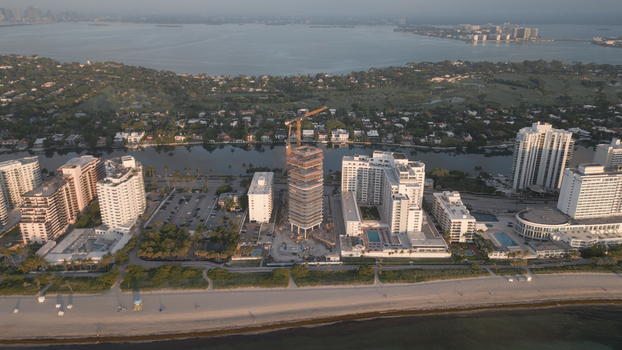Aerial view of a high rise building under construction with a crane surrounded by luxury hotels and residential buildings along the coastline in Miami Beach Florida United States. Aerial view of a high rise building under construction with a crane surrounded by luxury hotels and residential buildings along the coastline in Miami Beach Florida United States.