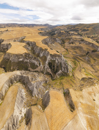 Aerial view of Toachi River Canyon featuring rugged cliffs golden agricultural fields and deep geological formations under a cloudy sky in Zumbahua Cotopaxi Ecuador. Aerial view of Toachi River Canyon featuring rugged cliffs golden agricultural fields and deep geological formations under a cloudy sky in Zumbahua Cotopaxi Ecuador.