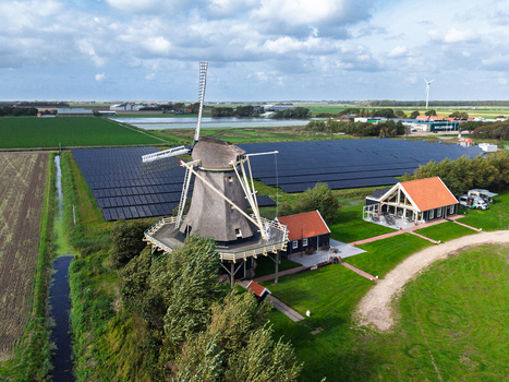 Aerial view of Molen De Hoop windmill surrounded by a large solar panel field and lush green agricultural fields in t Zand North Holland Netherlands. Aerial view of Molen De Hoop windmill surrounded by a large solar panel field and lush green agricultural fields in t Zand North Holland Netherlands.