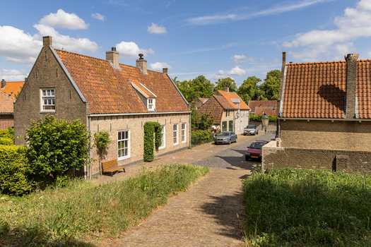 View of historic brick houses with orange tiled roofs along a cobblestone street in the charming town of Heusden North Brabant Netherlands.