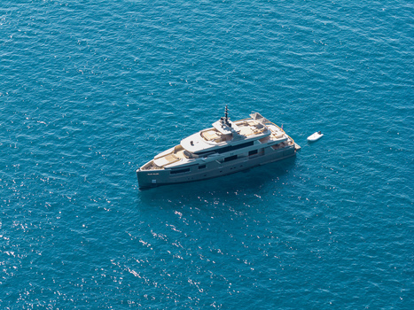 Aerial view of a luxury yacht cruising in the deep blue Mediterranean sea with a small tender boat trailing behind near Antibes Provence Alpes Cote d Azur France. Aerial view of a luxury yacht cruising in the deep blue Mediterranean sea with a small tender boat trailing behind near Antibes Provence Alpes Cote d Azur France.