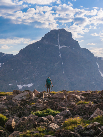 Aerial view of a hiker standing on a rocky ridge with a backpack looking towards the iconic Mount of the Holy Cross in the Sawatch Range under a bright blue sky Vail Colorado United States. Aerial view of a hiker standing on a rocky ridge with a backpack looking towards the iconic Mount of the Holy Cross in the Sawatch Range under a bright blue sky Vail Colorado United States.