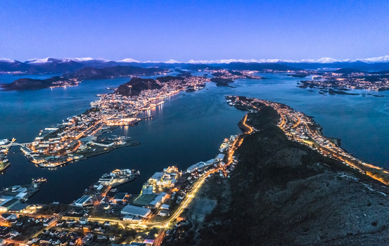 Aerial view of the coastal city of Alesund at twilight featuring illuminated streets harbor lights and surrounding islands Alesund More og Romsdal Norway. Aerial view of the coastal city of Alesund at twilight featuring illuminated streets harbor lights and surrounding islands Alesund More og Romsdal Norway.