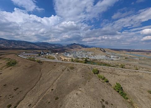 Aerial view of a large industrial quarry site with gravel piles processing machinery and surrounding arid landscape under a cloudy blue sky in Golden Colorado United States.