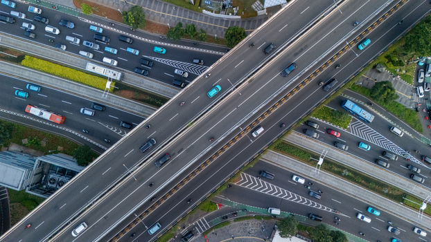 Aerial view of a busy highway interchange with cars and buses moving along multi lane roads surrounded by urban greenery in Jakarta Indonesia.