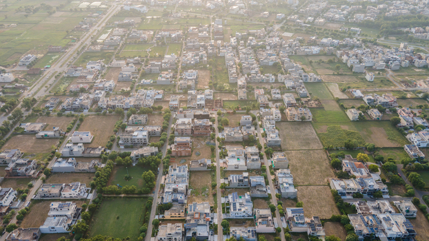 Aerial view of a residential neighborhood in Lahore featuring houses with rooftops solar panels and surrounding green spaces in Lahore Punjab Pakistan.
