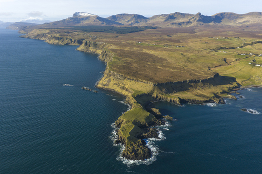 Aerial view of The Brother s Point with dramatic cliffs and the Trotternish Ridge mountains in the background in Culnacnoc Scotland United Kingdom. Aerial view of The Brother s Point with dramatic cliffs and the Trotternish Ridge mountains in the background in Culnacnoc Scotland United Kingdom.