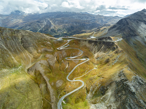 Aerial view of the winding Grossglockner High Alpine Road snaking through rugged mountain slopes and rocky terrain under a cloudy sky in Zell am See District Salzburg Austria.