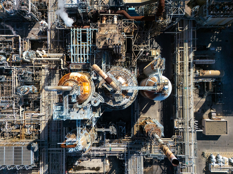 Aerial view of an industrial oil refinery complex featuring intricate piping networks large storage tanks and metal structures in Carson California United States.