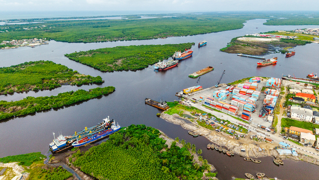 Aerial view of the port area in Satellite Town with cargo ships shipping containers and lush mangrove forests along the river in Lagos Lagos Nigeria.