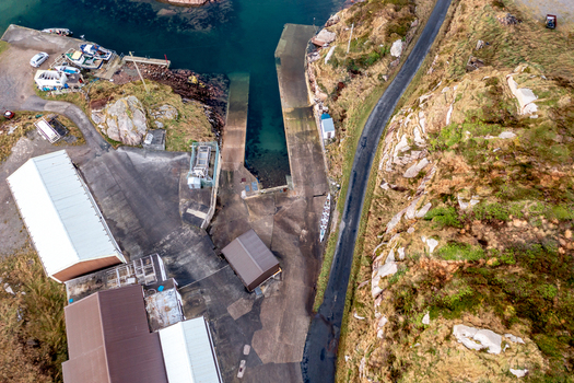 Aerial view of the small harbor and concrete slipway featuring surrounding rocky terrain coastal road and small buildings in Kincasslagh County Donegal Ireland. Aerial view of the small harbor and concrete slipway featuring surrounding rocky terrain coastal road and small buildings in Kincasslagh County Donegal Ireland.