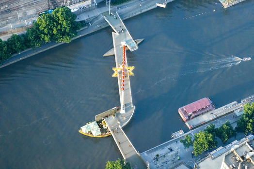 Aerial view of the Evan Walker Bridge spanning the Yarra River with pedestrian walkways and surrounding urban greenery in Melbourne Victoria Australia.