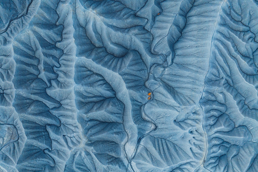 Aerial view of the intricate eroded blue grey clay formations of the badlands featuring deep ridges and gullies with small patches of orange sediment in Hanksville Utah United States.