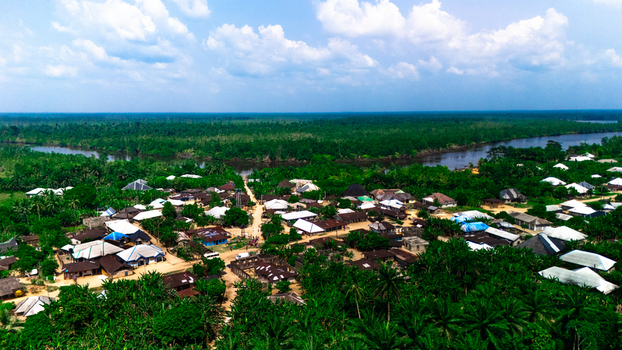 Aerial view of the village of Abua surrounded by dense tropical forest and palm trees with a winding river flowing through the landscape in Abua Rivers Nigeria. Aerial view of the village of Abua surrounded by dense tropical forest and palm trees with a winding river flowing through the landscape in Abua Rivers Nigeria.