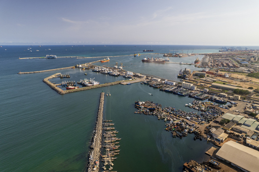 Aerial view of the bustling port city where the deep blue sea meets the industrial landscape with ships docked and the horizon fading into the sky Tema Ghana. Aerial view of the bustling port city where the deep blue sea meets the industrial landscape with ships docked and the horizon fading into the sky Tema Ghana.