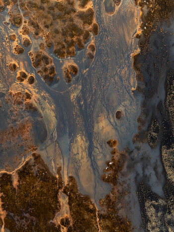 Aerial view of the intricate patterns of a glacial river delta featuring dark volcanic sediment and flowing water channels in Iceland. Aerial view of the intricate patterns of a glacial river delta featuring dark volcanic sediment and flowing water channels in Iceland.