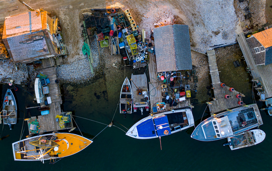 View of fishing boats moored at wooden docks next to rustic shacks on Martha s Vineyard with lobster traps and gear in Edgartown Massachusetts United States.