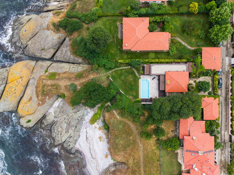 Aerial view of coastal villas with red roofs and a swimming pool situated on a rocky coastline with lush greenery and stone pathways in Lozenets Burgas Bulgaria.