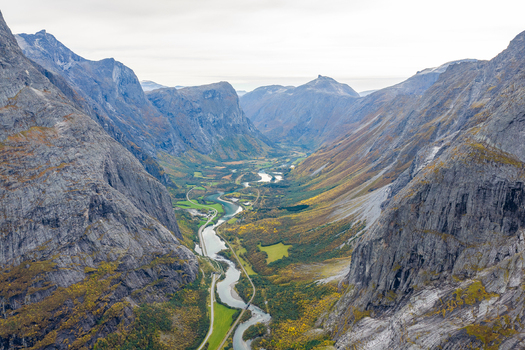 Aerial view of the deep Romsdalen valley with steep rocky mountain walls a winding river and autumn foliage in Andalsnes More og Romsdal Norway. Aerial view of the deep Romsdalen valley with steep rocky mountain walls a winding river and autumn foliage in Andalsnes More og Romsdal Norway.