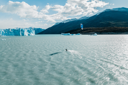 Aerial view of a kitesurfer on the turquoise waters of Lake Argentino near the Perito Moreno Glacier with mountains and icebergs in Perito Moreno Santa Cruz Province Argentina.