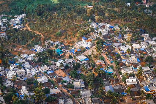 Aerial view of the Vizhinjam area featuring dense residential housing lush palm trees and narrow streets in Kovalam Keralam India. Aerial view of the Vizhinjam area featuring dense residential housing lush palm trees and narrow streets in Kovalam Keralam India.