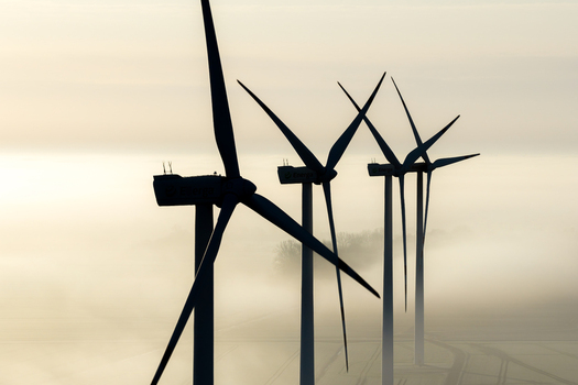 Aerial view of wind turbines rising above a thick layer of morning fog in a rural landscape in Poland. Aerial view of wind turbines rising above a thick layer of morning fog in a rural landscape in Poland.
