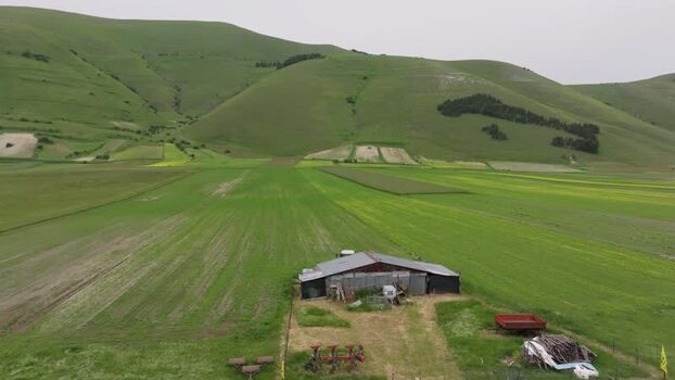 Aerial view of a farm building in the green fields of Italy.