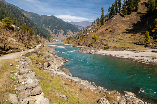 View of the turquoise Neelum River flowing through a mountain valley with scattered houses on the slopes Arang Kel Azad Kashmir Pakistan. View of the turquoise Neelum River flowing through a mountain valley with scattered houses on the slopes Arang Kel Azad Kashmir Pakistan.
