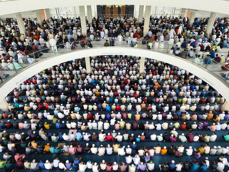 Dhaka Bangladesh 19 June 2026 Aerial view of a large crowd of people praying inside a mosque with rows of worshippers kneeling on the carpeted floor.
