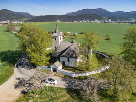 Aerial view of the historic Church of All Saints surrounded by lush green trees and a white stone wall in a rural landscape Ludrova Zilina Region Slovakia. Aerial view of the historic Church of All Saints surrounded by lush green trees and a white stone wall in a rural landscape Ludrova Zilina Region Slovakia.