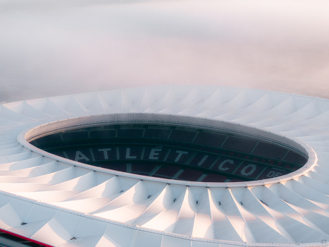 Aerial view of Riyadh Air Metropolitano Stadium with its distinctive white roof structure and seating bowl visible under soft morning light in Madrid Comunidad de Madrid Spain.