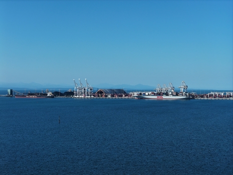 Aerial view of the Deltaport container terminal with large cargo ships gantry cranes and stacks of shipping containers along the waterfront in Delta British Columbia Canada. Aerial view of the Deltaport container terminal with large cargo ships gantry cranes and stacks of shipping containers along the waterfront in Delta British Columbia Canada.