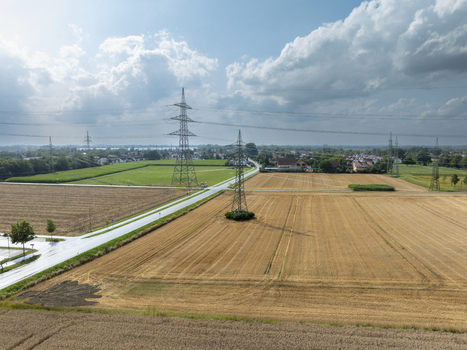 Aerial view of the rural landscape near Neufinsing with agricultural fields power lines and a road under a cloudy sky in Finsing Bayern Germany.