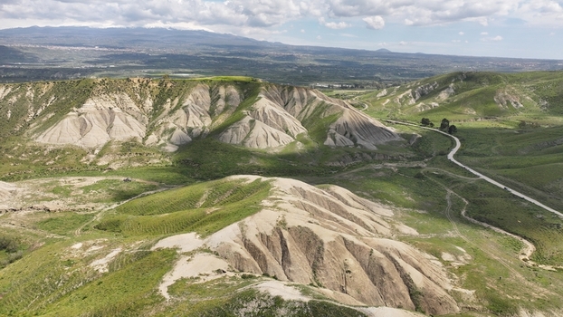 Aerial view of a landscape where rugged light colored hills meet pockets of vibrant green vegetation under a vast sky Centuripe Sicilia Italy. Aerial view of a landscape where rugged light colored hills meet pockets of vibrant green vegetation under a vast sky Centuripe Sicilia Italy.