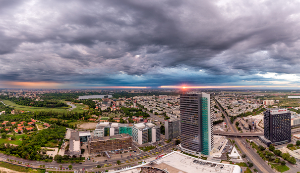 View of the modern skyline of Bucharest with tall office buildings lush green parks and a dramatic cloudy sky at sunset in Bucharest Bucharest Romania. View of the modern skyline of Bucharest with tall office buildings lush green parks and a dramatic cloudy sky at sunset in Bucharest Bucharest Romania.