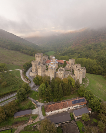 Aerial view of Manasija Monastery with fortified walls and towers nestled in a lush green valley with autumn foliage and a winding road in Despotovac Pomoravski okrug Serbia.