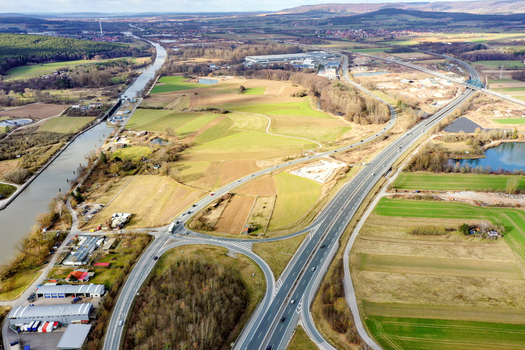 Aerial view of a highway interchange and the Main Donau Kanal surrounded by green fields and industrial buildings in Buttenheim Bavaria Germany. Aerial view of a highway interchange and the Main Donau Kanal surrounded by green fields and industrial buildings in Buttenheim Bavaria Germany.