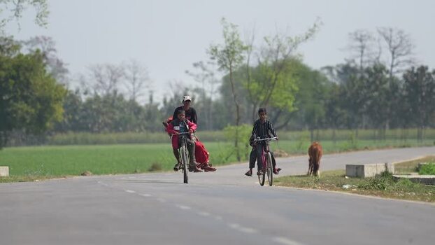 View of people riding bicycles on a rural road in Dhangadhi Nepal. View of people riding bicycles on a rural road in Dhangadhi Nepal.