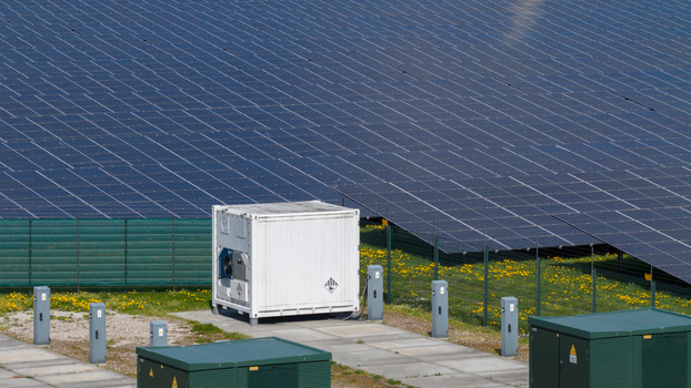 Aerial view of solar panels and a white power container on a solar farm with green electrical boxes and dandelions Warmenhuizen North Holland Netherlands. Aerial view of solar panels and a white power container on a solar farm with green electrical boxes and dandelions Warmenhuizen North Holland Netherlands.