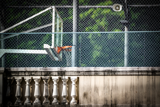 View of a basketball hoop behind a chain link fence above a weathered stone balustrade in Rio de Janeiro Rio de Janeiro Brazil.