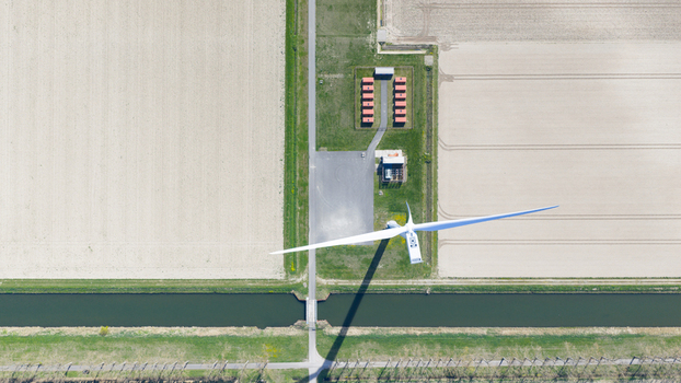 Aerial view of a large wind turbine with its shadow stretching over a canal and agricultural fields Middelharnis South Holland Netherlands. Aerial view of a large wind turbine with its shadow stretching over a canal and agricultural fields Middelharnis South Holland Netherlands.