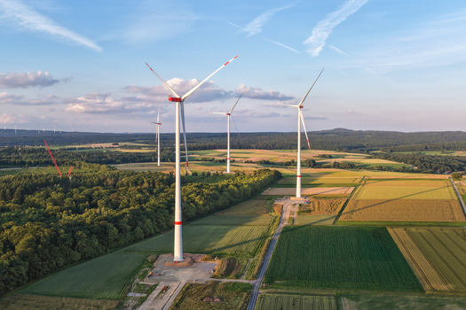 Aerial view of wind turbines standing in agricultural fields and forests during golden hour in Hofgeismar Hessen Germany.