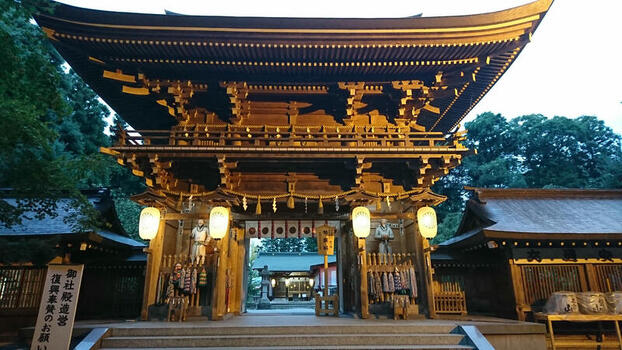 View of the traditional wooden gate at Isasumi Shrine Honden illuminated by glowing paper lanterns in Aizumisato Fukushima Japan.