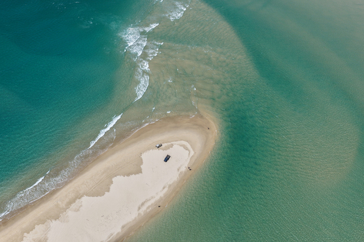 Aerial view of Moreton Island sand spit with turquoise water and parked vehicles in Kooringal Queensland Australia. Aerial view of Moreton Island sand spit with turquoise water and parked vehicles in Kooringal Queensland Australia.